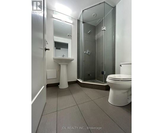 A white toilet sits next to a walk-in shower in a bathroom.