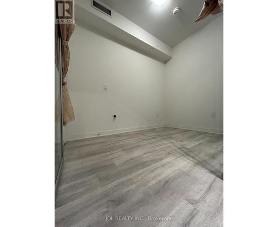 A room with wooden flooring and a Realtor sign on the wall.
