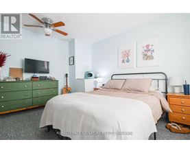 A bedroom with a bed, dresser, and ceiling fan.