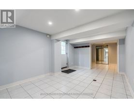 A spacious room with white tiled flooring and a doorway leading to another room.