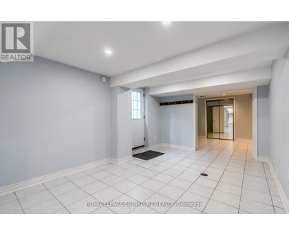 A spacious room with white tiled flooring and a doorway leading to another room.