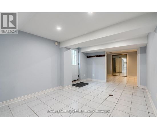 A spacious room with white tiled flooring and a doorway leading to another room.