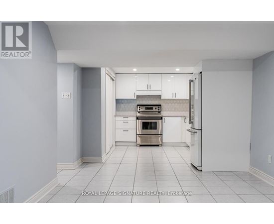A white kitchen with a refrigerator, oven, and cabinets.