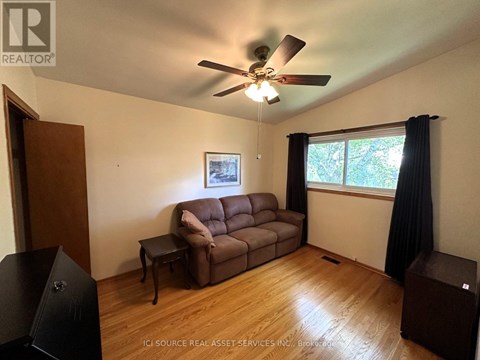 A living room with a brown couch and a ceiling fan.