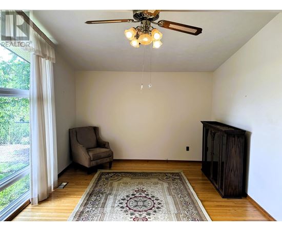 A room with a ceiling fan and a rug on the floor.