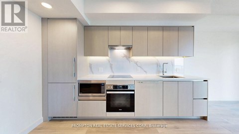 A modern kitchen with a stainless steel refrigerator and oven.