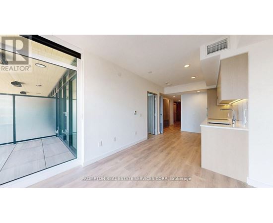 A spacious room with a glass door leading to a balcony.