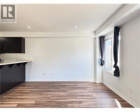 A room with wooden flooring and a window with black curtains.