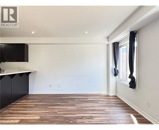 A room with wooden flooring and a window with black curtains.
