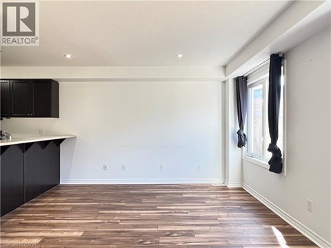 A room with wooden flooring and a window with black curtains.