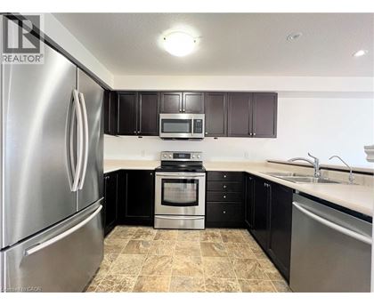 A kitchen with black cabinets and a stainless steel refrigerator.