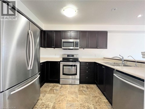 A kitchen with black cabinets and a stainless steel refrigerator.