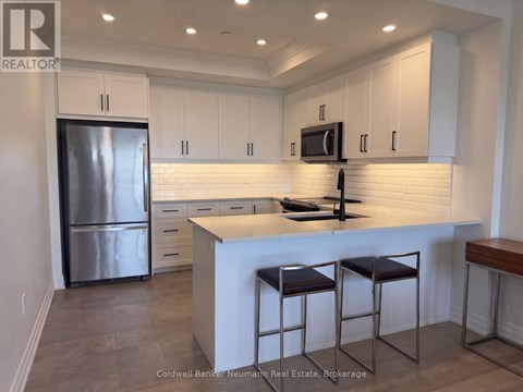 A kitchen with white cabinets and a stainless steel refrigerator.