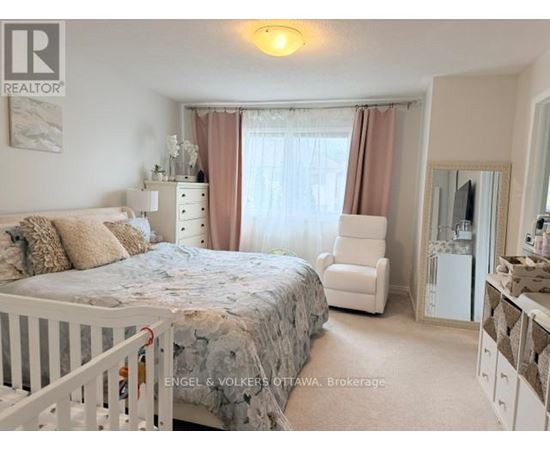 A bedroom with a white bed and a white chair.