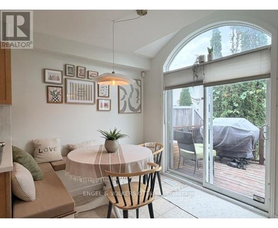 A living room with a white table and a couch with a green pillow on it.