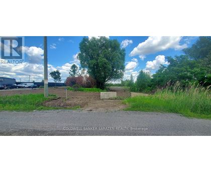 A sign for Coldwell Banker Sarazen Realty Brokerage is in the foreground of a grassy area.
