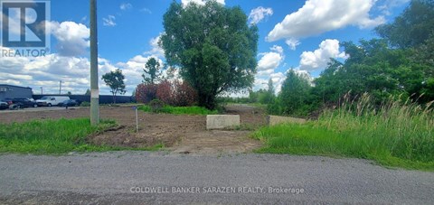 A sign for Coldwell Banker Sarazen Realty Brokerage is in the foreground of a grassy area.
