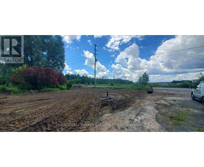A dirt road with a white car parked on the side.