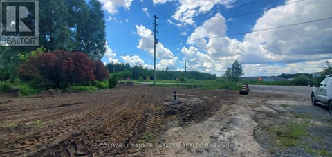 A dirt road with a white car parked on the side.