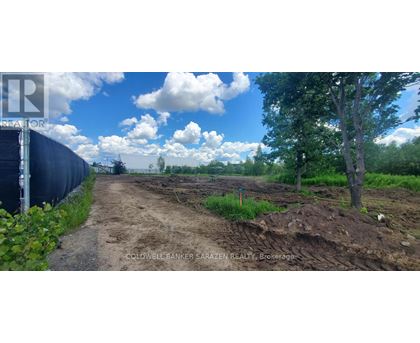 A dirt road leads to a construction site with a fence on the left.