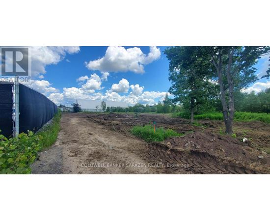 A dirt road leads to a construction site with a fence on the left.