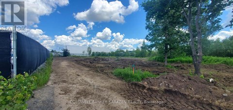 A dirt road leads to a construction site with a fence on the left.