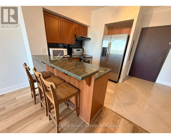 A kitchen with a table and chairs in front of a refrigerator.