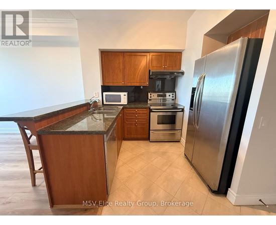A kitchen with a refrigerator, microwave, and oven.