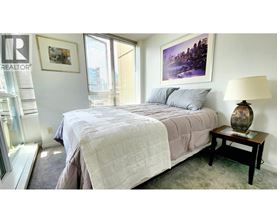 A bedroom with a large bed and a painting on the wall.