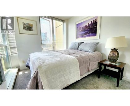 A bedroom with a large bed and a painting on the wall.