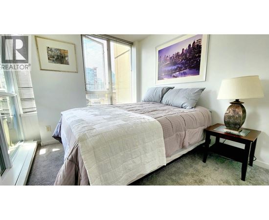 A bedroom with a large bed and a painting on the wall.