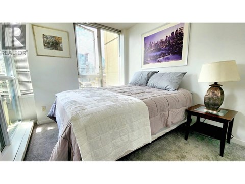 A bedroom with a large bed and a painting on the wall.