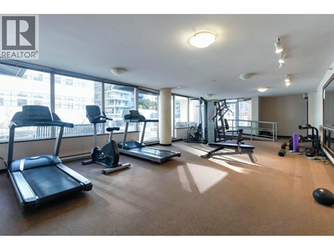 A gym with treadmills, exercise bikes, and weights is shown.