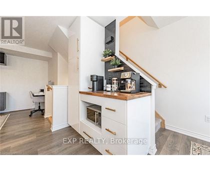 A kitchen with a white cabinet and drawers, a stove top oven, and a plant on top of the cabinet.