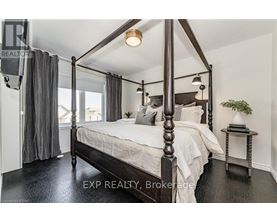 A bedroom with a four poster bed and a small table with a plant on it.