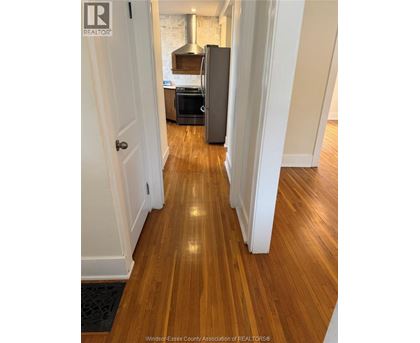 A hallway with wooden floors and white walls.