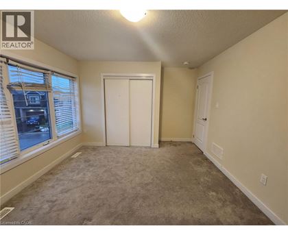 A bedroom with a carpeted floor and a window with blinds.