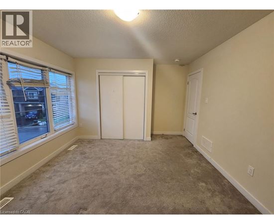 A bedroom with a carpeted floor and a window with blinds.