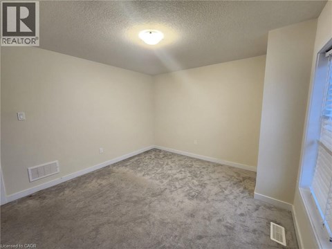 A room with a carpeted floor and a window on the right side.