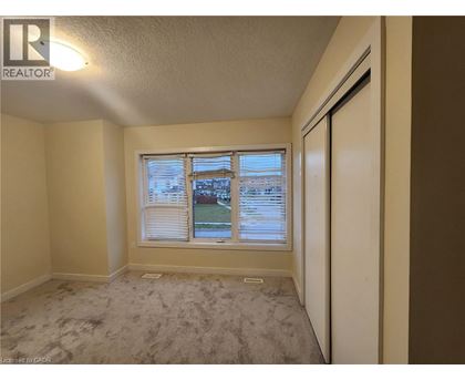 A room with a window showing a view of a street and houses.
