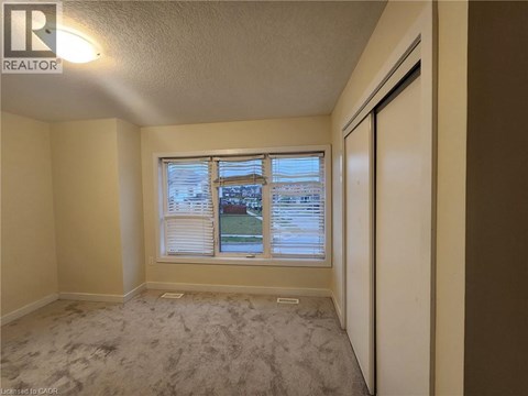 A room with a window showing a view of a street and houses.