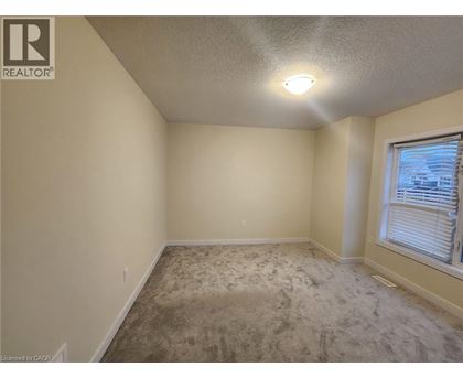 A room with a carpeted floor and a window with blinds.