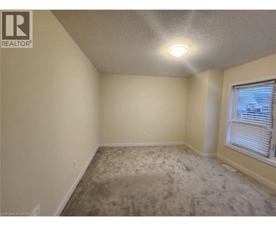 A room with a carpeted floor and a window with blinds.