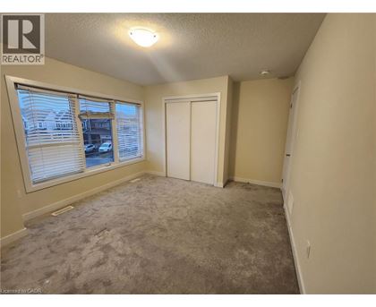 A room with a carpeted floor, a window with blinds, a door, and a ceiling light.