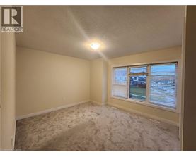 A room with a carpeted floor and a window showing a view of a street.