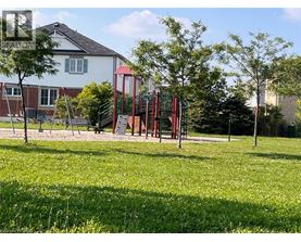 A playground with a red swing set and a green lawn.