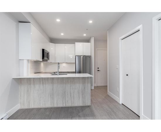 A modern kitchen with a stainless steel refrigerator and a wooden island.
