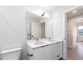 A white bathroom with a toilet, sink, and mirror.