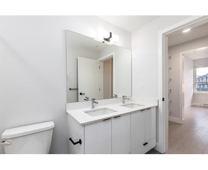 A white bathroom with a toilet, sink, and mirror.
