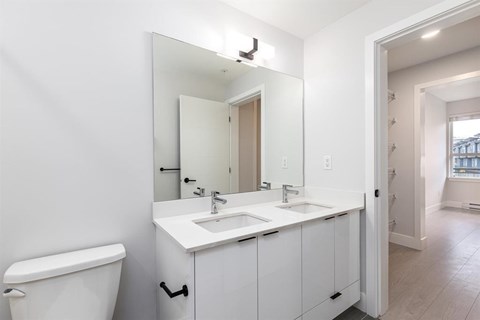 A white bathroom with a toilet, sink, and mirror.